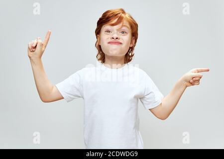 red-haired boy with a stupid expression on his face gestures with his hands to point a finger towards Copy Space Stock Photo