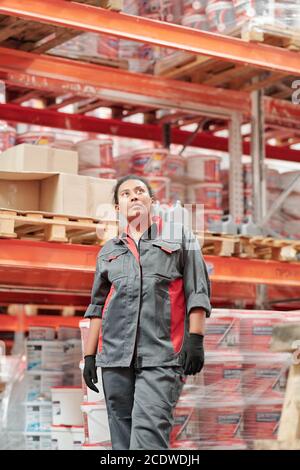 Young female worker of contemporary warehouse in uniform and gloves Stock Photo