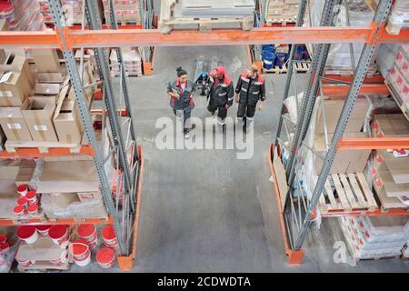 Two young intercultural male workers of warehouse talking to head manager Stock Photo
