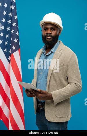 Young bearded African-american engineer in helmet using digital tablet Stock Photo