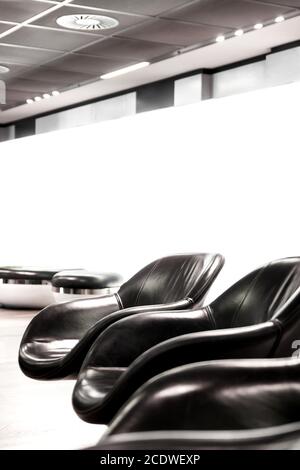 Black leather armchair in bright waiting area with white wall Stock Photo