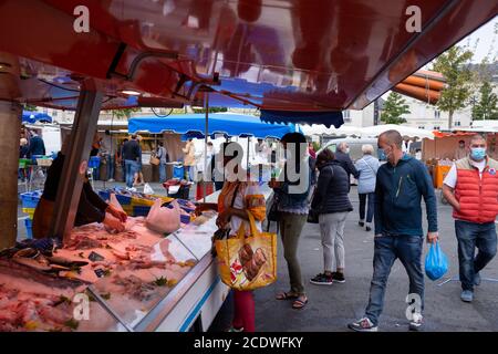 Angers, France - August 29 2020: people wearing face protective mask while shopping in the market place at France to prevent coronavirus, concept of wearing masks outdoor is mandatory Stock Photo
