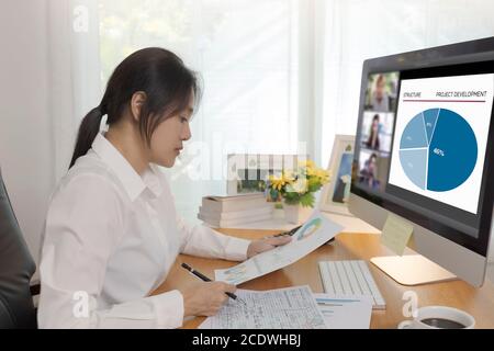 Asian business women working at home online meeting with video conference on computer. Business people using computer online meeting and speaking with Stock Photo