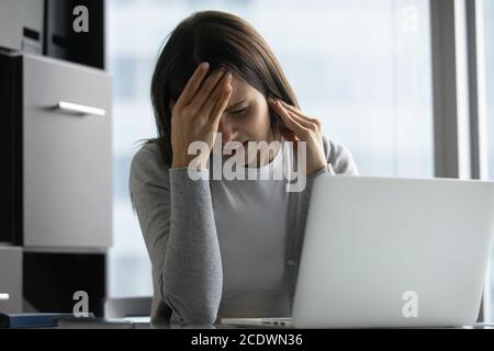 Unhappy stressed businesswoman touching head, suffering from migraine Stock Photo