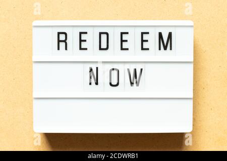 Lightbox with word redeem now on wood background Stock Photo