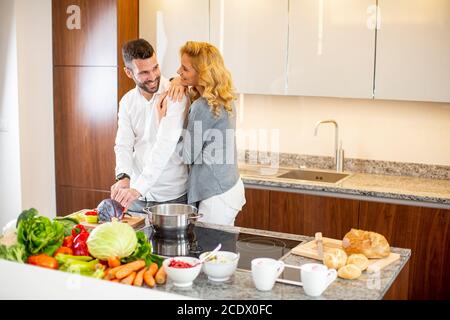 View at young man helping his girlfriend cooking in modern kitchen Stock Photo