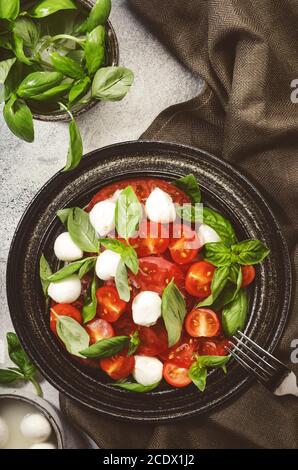 Tasty caprese salad with ripe red tomatoes and mozzarella cheese with fresh green basil leaves. Italian food. Top view Stock Photo
