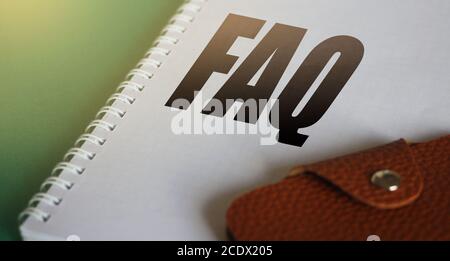 FAQ abbreviation printed in copybook and brown leather wallet. Selective focus . Business support team help desk Concept Stock Photo