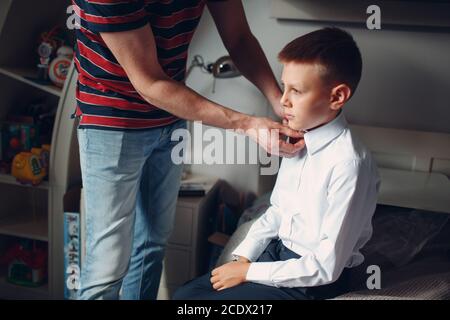 Father helping son buttoning his shirt and dressing uniform preparation back to school. Stock Photo
