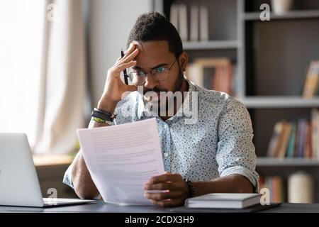 African American man dissatisfied by bad news received in letter Stock Photo