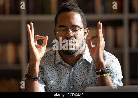 Close up mindful African American man wearing glasses meditating Stock Photo