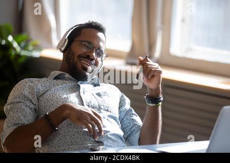 Satisfied relaxed African American man wearing headphones enjoying music Stock Photo