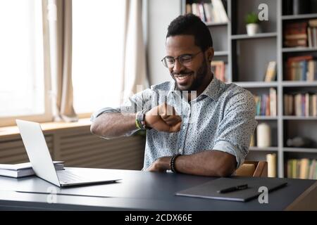 Smiling African American businessman checking time, looking at wristwatch Stock Photo