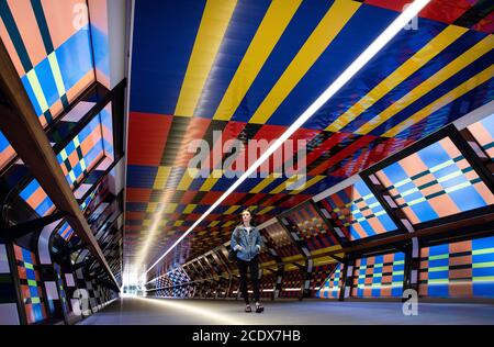 Francesca Clemens walks past new artwork from contemporary artist Camille Walala, which reimagines the Adams Plaza Bridge in Canary Wharf, for the debut London Mural Festival. Stock Photo