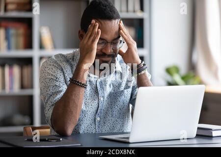Stressed African American businessman touching temples, suffering from headache Stock Photo