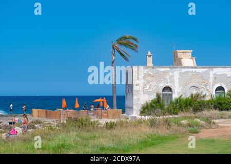 Wonderful Mediterranean coast in Puglia, South Italy, with finca or old stone white house and palm tree, blue flag Stock Photo