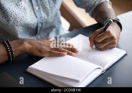 Close up African American businessman writing in notebook, making notes Stock Photo
