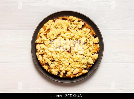 Delicious juicy plum cake in a round plate close up isolated on white wooden background Stock Photo