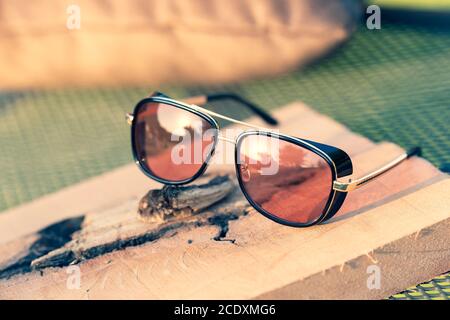 Retro sunglasses model with red lenses shoot in a summer day closeup. Selective focus
