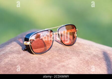 Retro sunglasses model with red lenses shoot in a summer day closeup. Selective focus