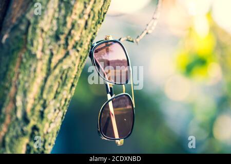 Retro sunglasses model with red lenses shoot in a summer day in nature closeup. Selective focus