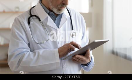 Close up senior doctor using digital tablet, medical apps Stock Photo