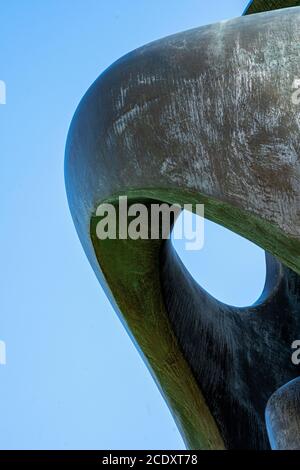 Large brass curved sculpture against blue sky textured background image abstract Stock Photo