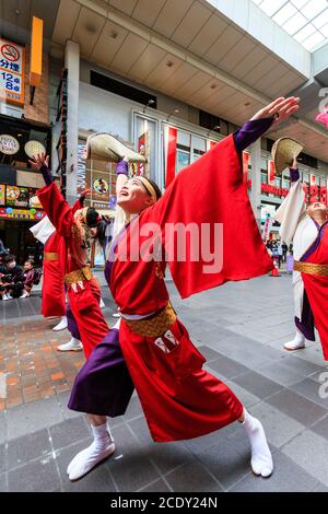 Japanese team of yosakoi dancers wearing long sleeved yukata and using naruko, wooden clappers, dancing in a shopping arcade, during Kyusyu Gassai. Stock Photo