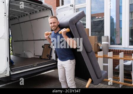 Man Lifting Sofa Or Couch Furniture. Moving Home Stock Photo