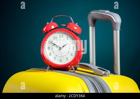 Alarm clock on luggage. Travel and holiday concept. Studio shot Stock Photo