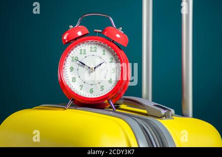 Alarm clock on luggage. Travel and holiday concept. Studio shot Stock Photo