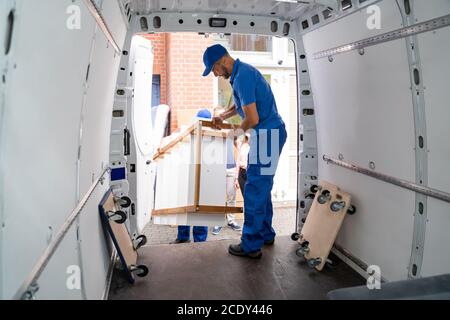Happy Family Couple Watching Movers Unload Furniture From Truck Stock Photo