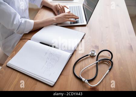 Close up young woman doctor working on laptop in hospital Stock Photo