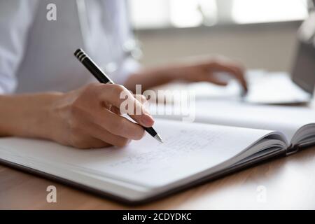 Close up female doctor filling documents and using laptop Stock Photo