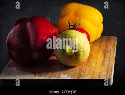 Vegetables and Fruits over a Rustic Chopping Board in Low Key Lighting Stock Photo