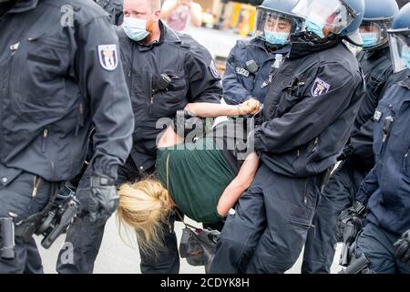 Berlin, Germany. 30th Aug, 2020. Police officers carry a woman at the Victory Column in a protest against the Corona measures. Credit: Christoph Soeder/dpa/Alamy Live News Stock Photo