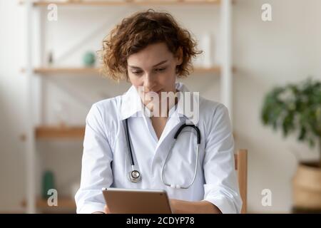 Close up focused confident woman doctor using digital tablet Stock Photo