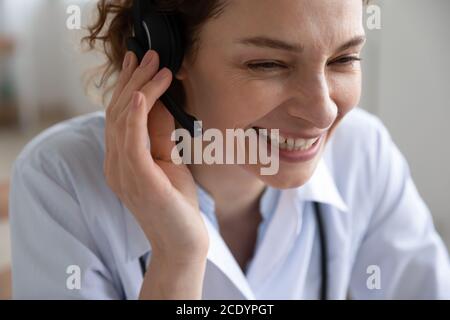 Close up smiling young woman doctor wearing headset working online Stock Photo