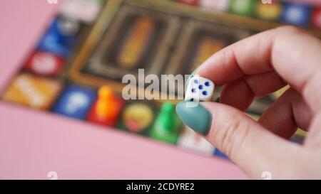 Hand throws the dice on the background of colorful blurred Board games, gaming moments Stock Photo
