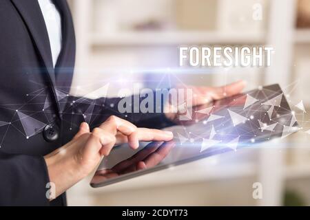 Close up hands using tablet with FORESIGHT inscription, modern business technology concept