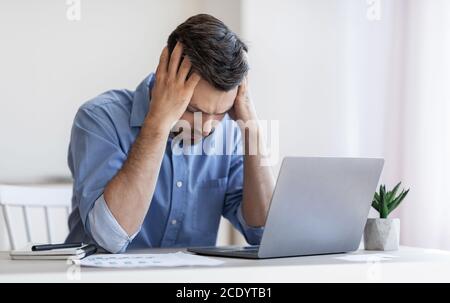 Bankruptcy Concept. Depressed male entrepreneur suffering from business failure, sitting at workplace Stock Photo
