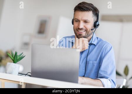 Hotline Support Service. Male call center operator in headset working with laptop Stock Photo
