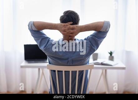Home Office Relax. Rear view of male freelancer resting at workplace Stock Photo