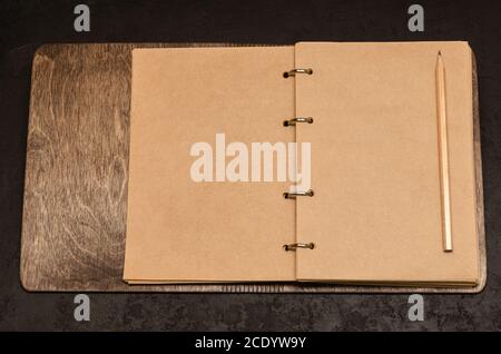 Eco friendly open notebook in wooden cover with blank sheets with space for your text and pencil on black background. To do list. Time to take stock Stock Photo