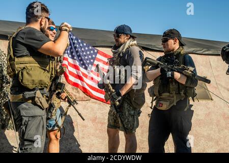 Professional shooters speaking cheerfully while giving advice to young men at shooting range Stock Photo