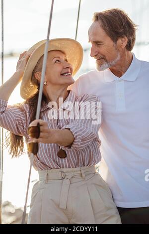 Romantic mature couple looking at each other while standing on a sailboat during sunny day