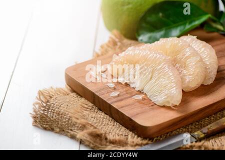 fresh peeled Pomelo or grapefruit on  wood plate. Seasonal fruit of Thailand, pomelo or citrus grandis, peeled on white wood background. Stock Photo