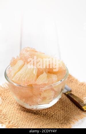fresh peeled Pomelo or grapefruit in glass bowl on   white wood blackground. Seasonal fruit of Thailand, Stock Photo