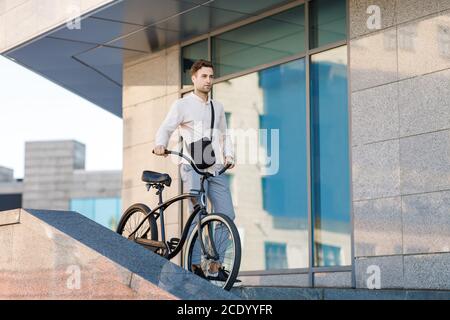 On the way to work on eco transport. Stylish hipster going down the steps with bike Stock Photo