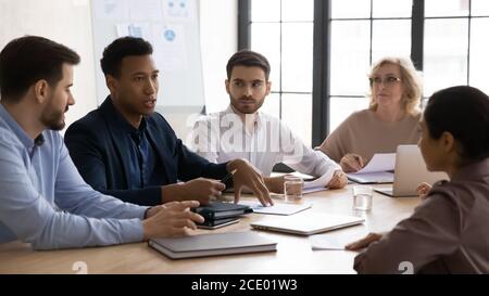 Focused mixed race business people listening to african american colleague. Stock Photo
